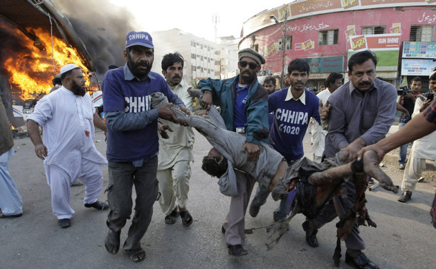 Pakistani volunteers carry a wounded bus passenger following a blast in Karachi, Pakistan on Saturday, Dec. 29, 2012. The blast that ripped through the bus set the vehicle on fire and reduced it to little more than a charred skeleton, killing scores of people and left many injured. Police were trying to determine whether the explosion was caused by a bomb or a gas cylinder, said police spokesman. Many buses in Pakistan run on natural gas. (AP Photo/Fareed Khan)